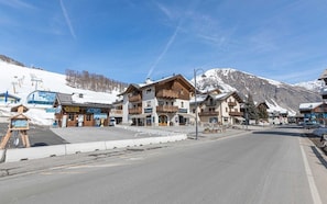 A mountain town with a ticket shop, wooden buildings, and a snow-covered mountain in the background.
