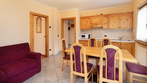 Un coin repas avec une table et des chaises en bois, un canapé rouge et des meubles de rangement en bois.