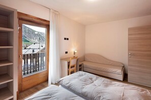 A bedroom with a bed, a desk, a chair, and a wardrobe.