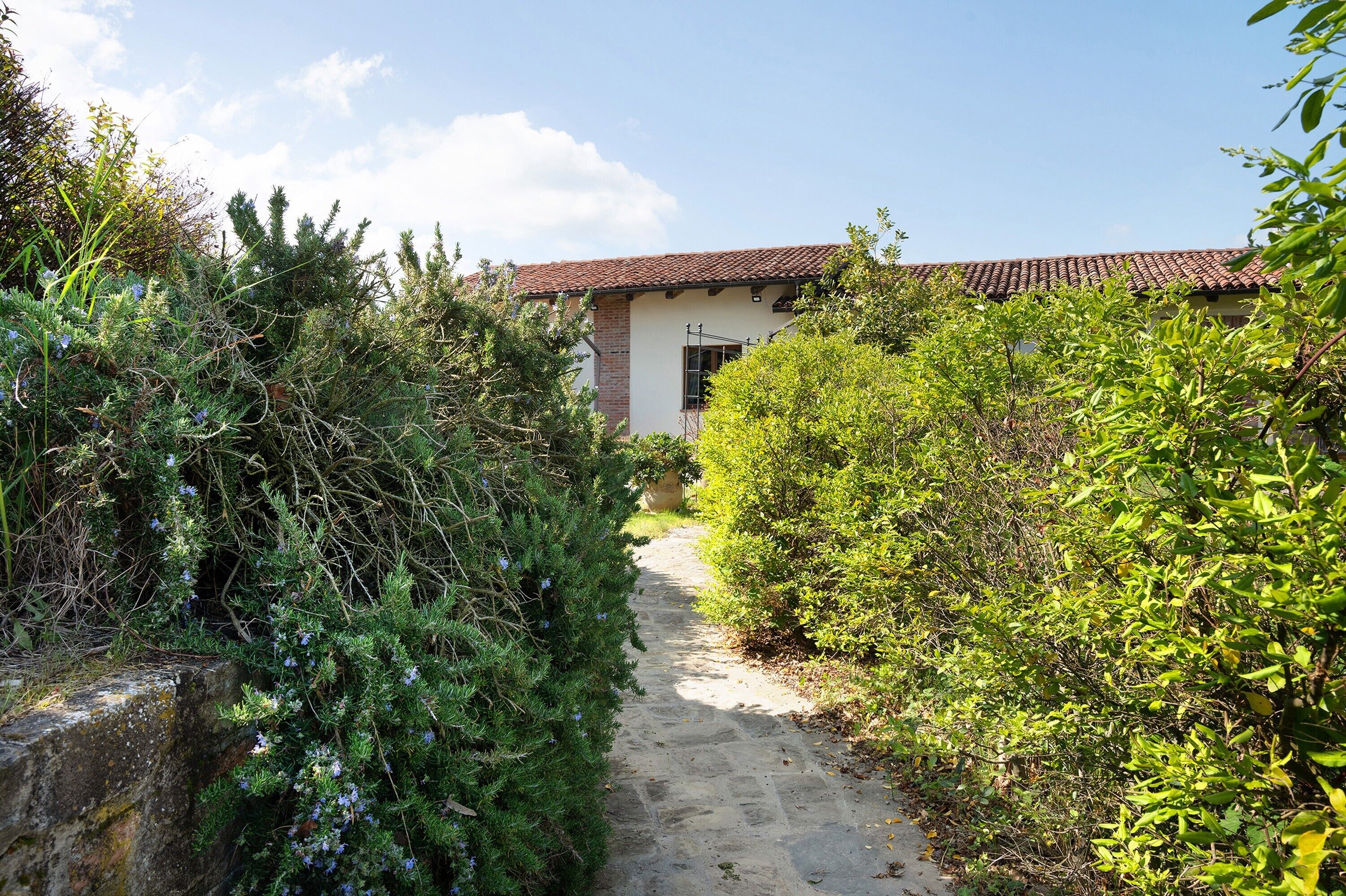 A stone pathway leading to a building with a red-tiled roof.