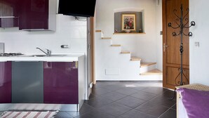 Una cocina moderna con estufa integrada, televisor de pantalla plana y una escalera que conduce a una puerta de madera.