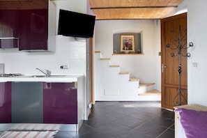 Una cucina moderna con piano cottura integrato, una TV a schermo piatto e una scala che conduce a una porta in legno.