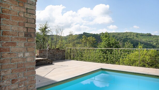 Une piscine avec vue sur une colline boisée.