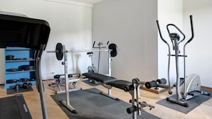 Une salle de sport équipée de matériel de musculation, d’un banc et d’un vélo d’appartement.