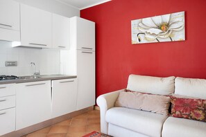 A modern kitchen with white cabinets and a red accent wall.