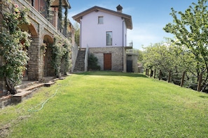 Un edificio su due piani con facciata in pietra, una porta in legno e una piccola finestra.