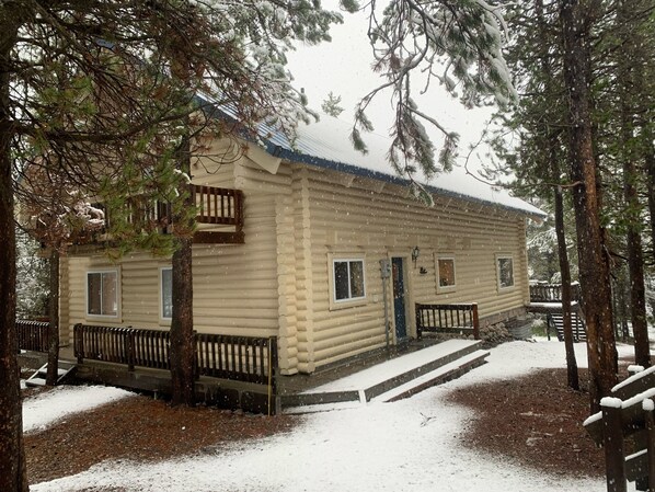 A log cabin with a porch, surrounded by trees and covered in snow. - Sleeps 14 Yellowstone Cabin | King Suites + Bunks (Island Park)