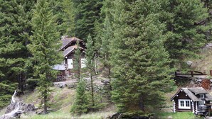 Una cabaña con fachada de madera, rodeada de un bosque tupido y un lago.