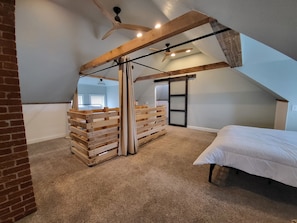 Enjoy a loft-style ceiling with exposed beams and a central fan, a comfortable bed, and a bench.