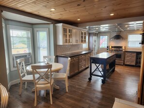A kitchen with wooden cabinets, a central island, and a dining area with chairs.