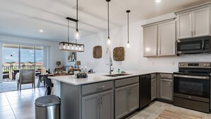 A modern kitchen with stainless steel appliances, a large island, and pendant lighting. - 3BR Champions Gate Home w/ Oasis Club (Davenport)