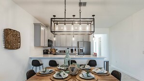 A modern kitchen with white cabinets, a central island, and a hanging light fixture. - 3BR Champions Gate Home w/ Oasis Club (Davenport)