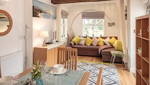 Un salon moderne avec un canapé, une table à manger et une grande fenêtre.