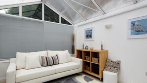 Un salon moderne avec un canapé blanc, un tapis à motifs géométriques et une étagère en bois.