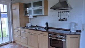 Una cocina con gabinetes de madera, una campana extractora de acero inoxidable, horno empotrado y cafetera.