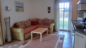 Una sala de estar con sofá, mesa de centro y una zona de cocina con fregadero y estufa.