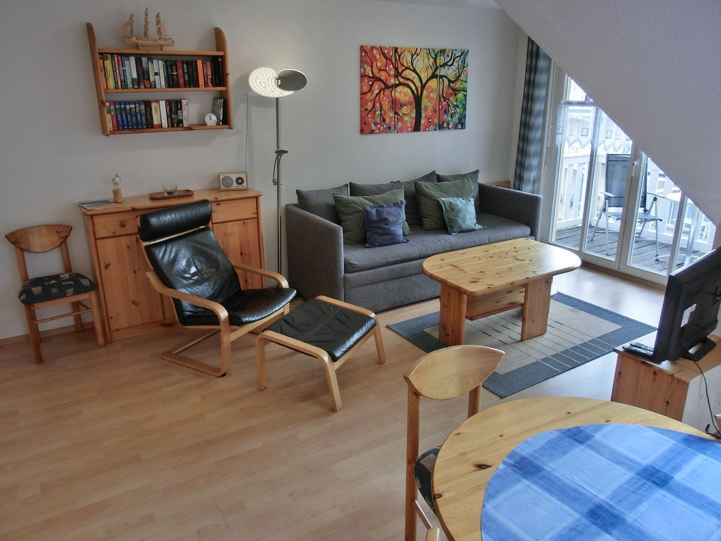 Una sala moderna con un sofá, una mesa de centro de madera, un sillón de cuero negro, un escritorio de madera y una estantería.