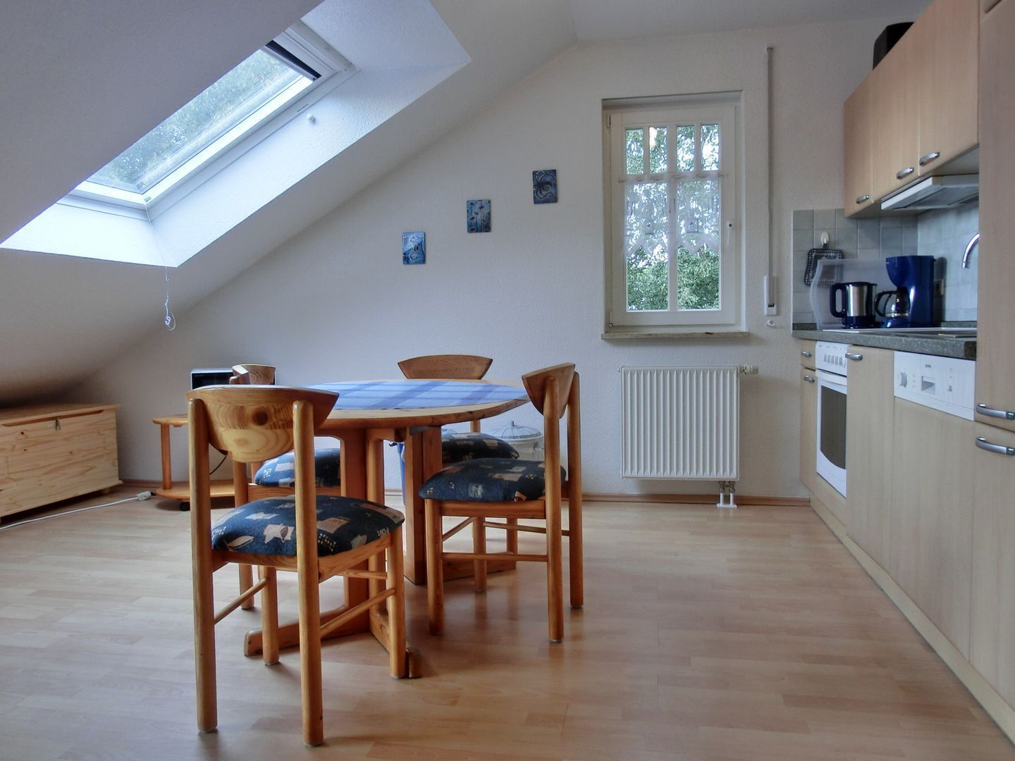 A kitchen with a skylight, a dining table with chairs, and a window.