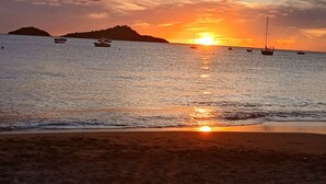 A beach at sunset with boats on the water and a distant island. - Magnificent Zen Villa with swimming pool in a 4000 m2 garden (Bouillante)