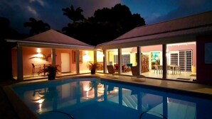 A poolside area with a clear view of the pool, a dining area with chairs and tables, and a covered seating area with a lamp. - Magnificent Zen Villa with swimming pool in a 4000 m2 garden (Bouillante)