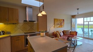 Una cocina moderna con armarios de madera, una isla central y un comedor con mesa de vidrio.
