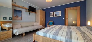 A bedroom with a bed, a sofa, a chair, and a wardrobe.