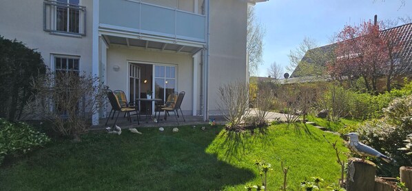 A two-story building with a covered patio area featuring a table and chairs.