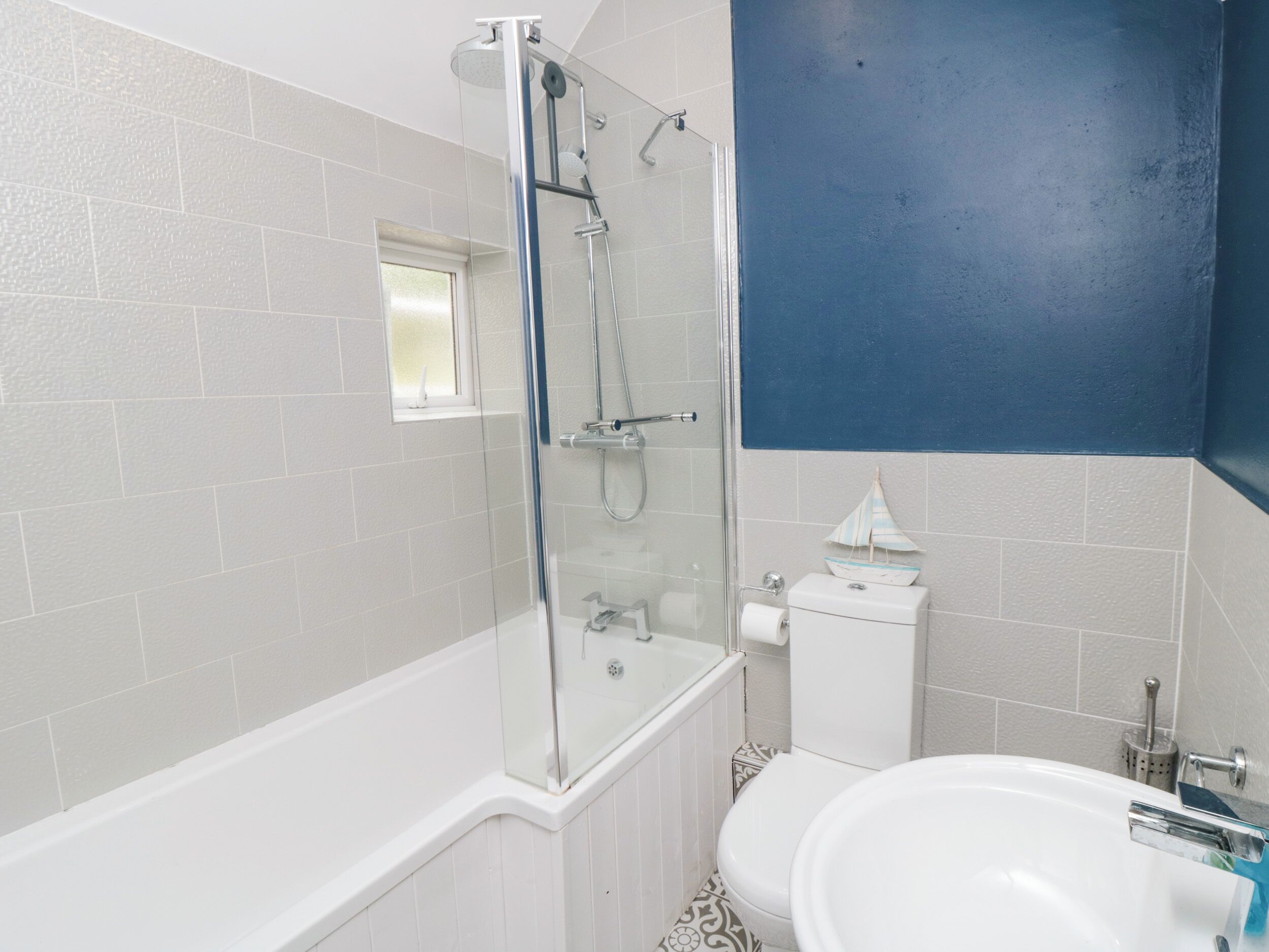 Un baño con ducha de vidrio, bañera blanca, inodoro blanco y lavamanos.