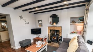 A cozy living room with a fireplace, a television, and a comfortable sofa. - Puffin Cottage (Scarborough)