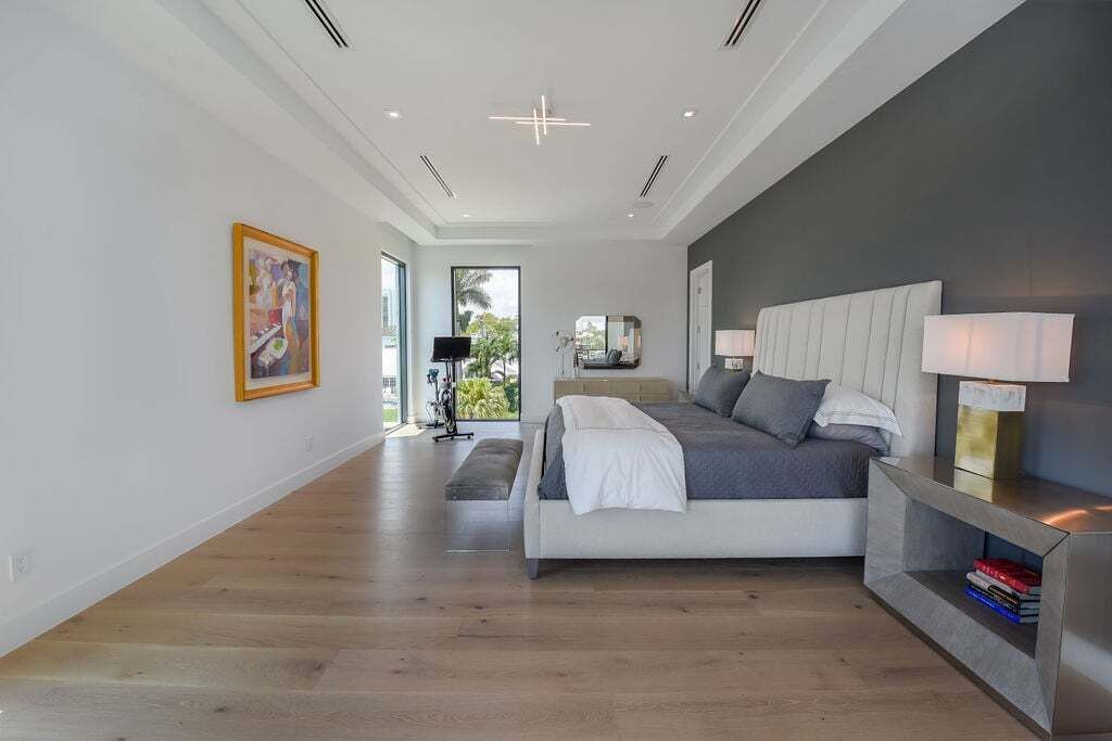 A modern bedroom with a large bed, bedside lamps, and a view to the outdoors.