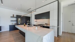 Eine moderne Küche mit einer großen Kochinsel, dunklen Schränken und einer eleganten Arbeitsplatte.