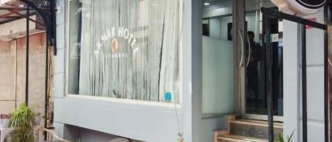 El exterior del Hotel Armar, con alfombra roja en la entrada, fachada de vidrio y un cartel con el nombre del hotel.