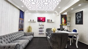 A modern waiting area with a sofa, chairs, a desk, and a TV. - Armar Hotel (Istanbul)