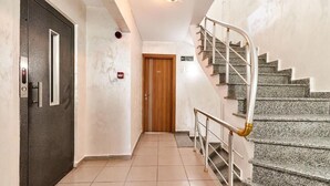 A hallway with a wooden door, a staircase with metal railings, and a tiled floor. - Armar Hotel (Istanbul)