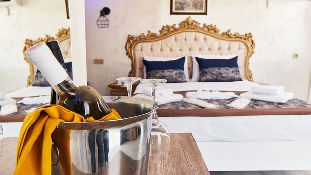 A hotel room with a bed, a bedside table with a bottle and glasses, and a wooden table with a bottle and a cloth. - Armar Hotel (Istanbul)
