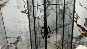 A bathroom with a glass shower enclosure and marble walls. - Armar Hotel (Istanbul)