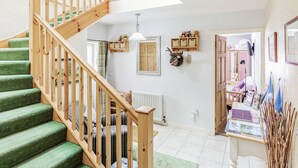A staircase with green carpeted steps and wooden railings, a radiator, a shelf with stuffed animals, and a mirror on the wall. - Drimnatorran Farm Lodge (Acharacle)