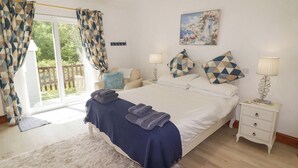 Un dormitorio con cama, mesitas de noche, cortinas en la ventana y una pintura en la pared, con vistas al exterior.