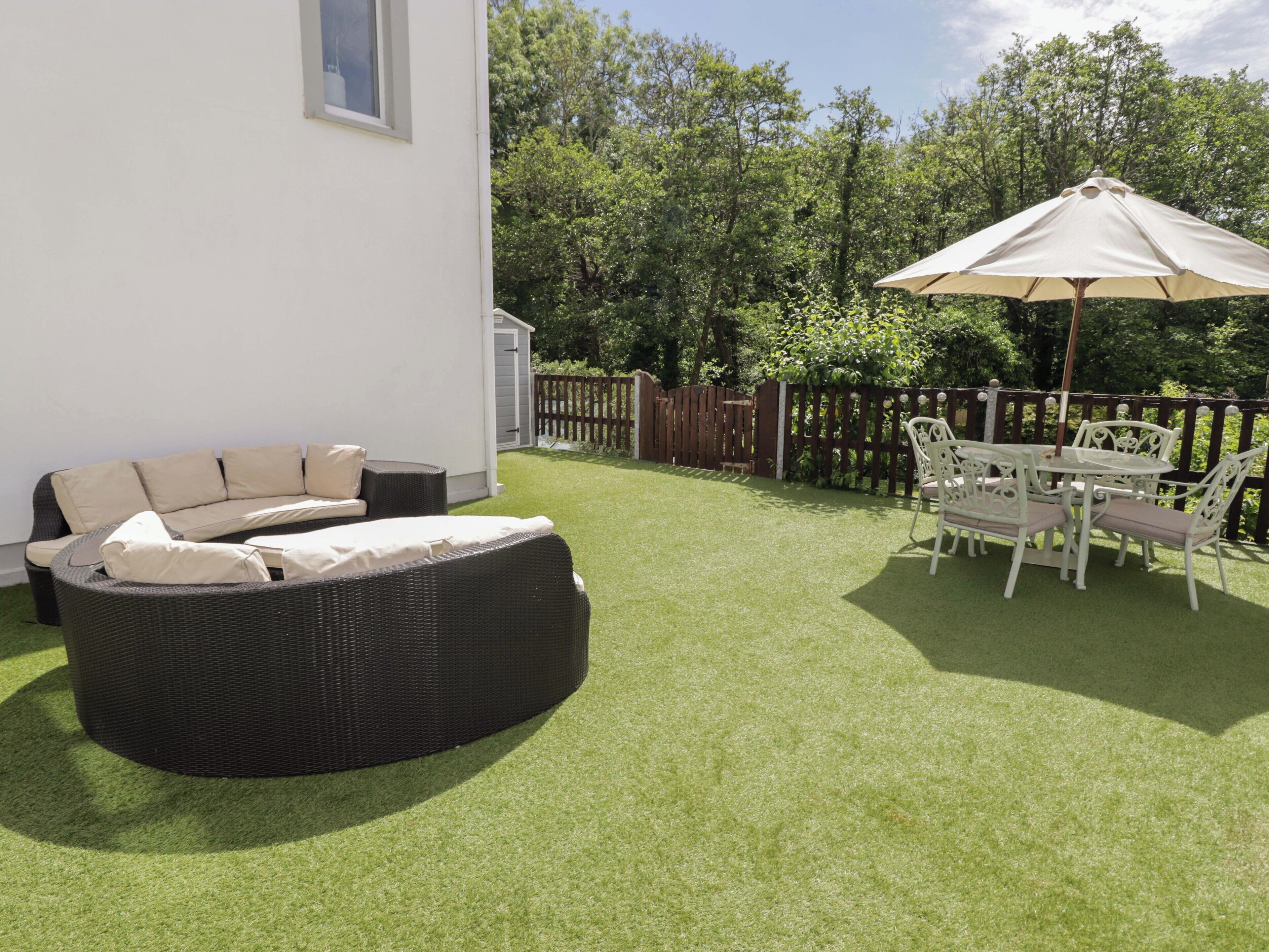 A patio with a wicker sofa, a dining table with chairs, and an umbrella.