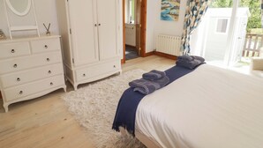 Un dormitorio con cama, cómoda, espejo, una puerta que da a un balcón y un cuadro en la pared.