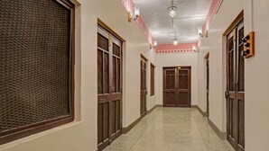 A hallway with wooden doors, a patterned wall, and a tiled floor. - Treebo The Regal House, Near Fateh Sagar Lake (Udaipur)