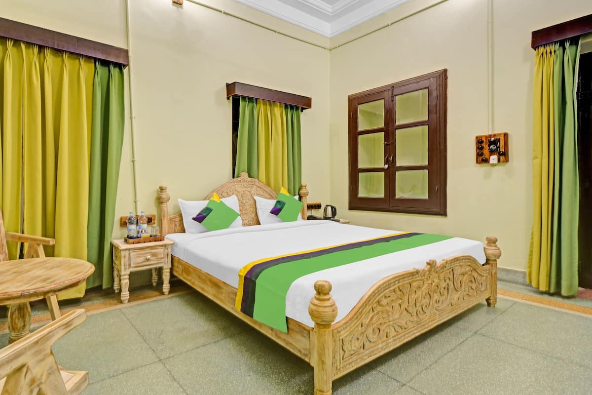 A neatly arranged bedroom with a bed, a chair, a nightstand, and a window with curtains.