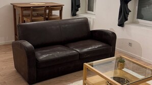 A living room with a dark leather sofa, a glass coffee table, a wooden dining table, and a white furry rug. - Apartment terrace WIFI cable channels 4 pers Lille fac de droit Moulins (Lille)