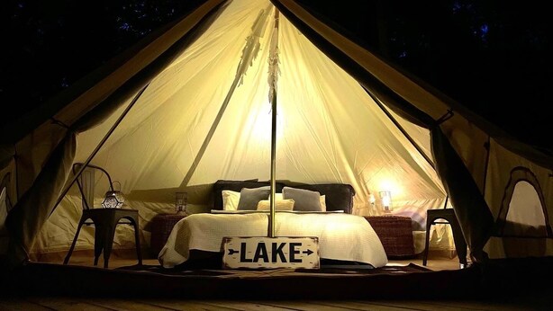 A tent with a bed, a sign reading "LAKE", and a lantern.