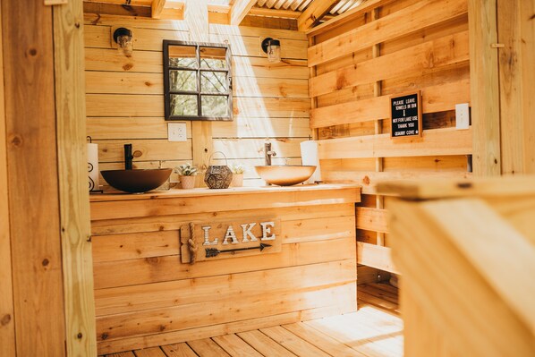 A wooden cabin interior with a sink, a sign reading 'LAKE', and a window.