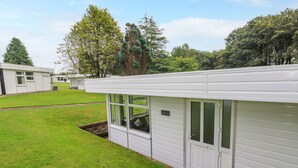 A row of white mobile homes with a grassy yard and trees in the background. - Saltwater (Haverfordwest)