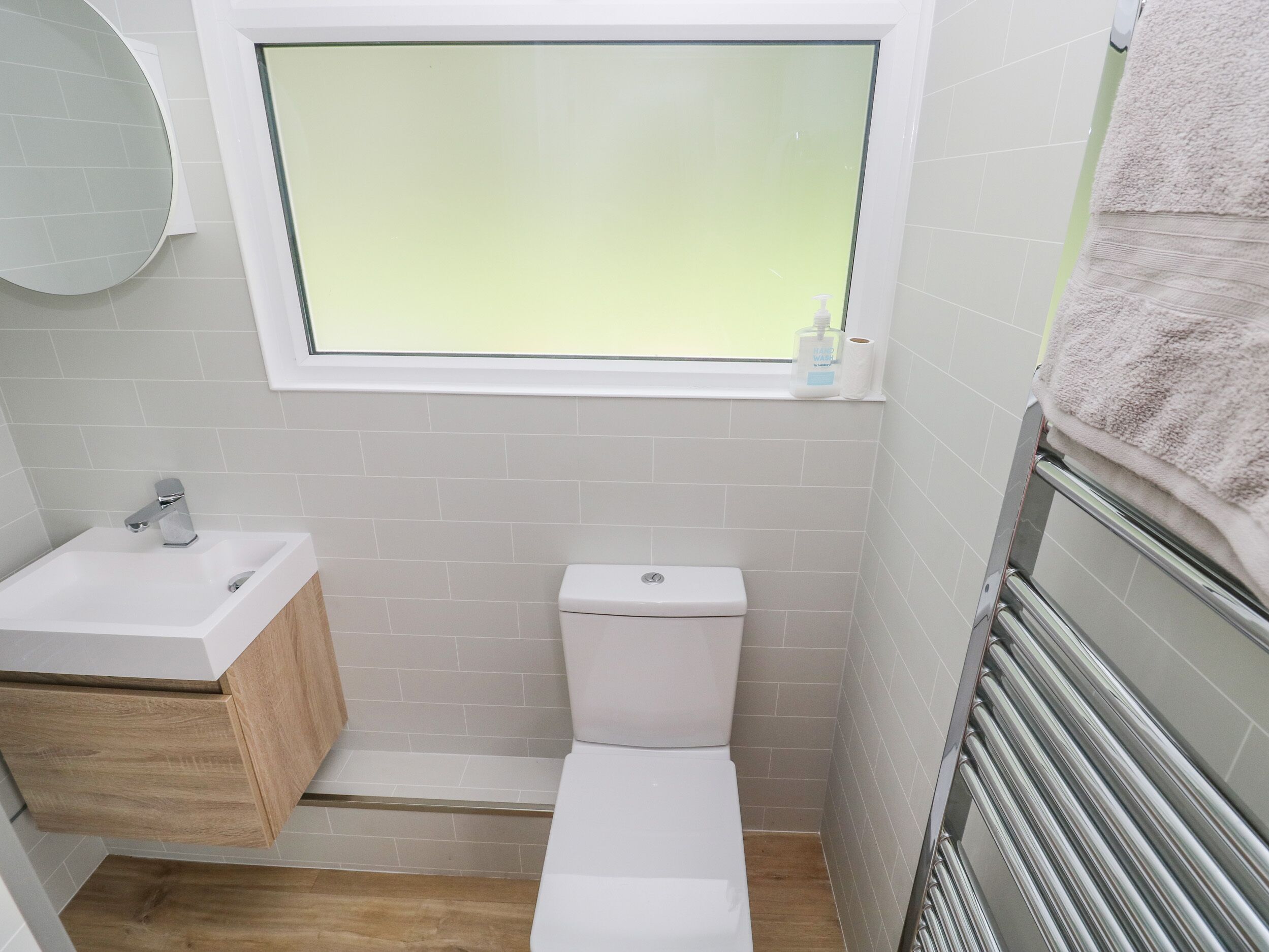 Un baño pequeño con un lavamanos blanco, un inodoro y una ventana sobre el inodoro.