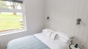 A bedroom with a bed, a window, and a small stool. - Saltwater (Haverfordwest)