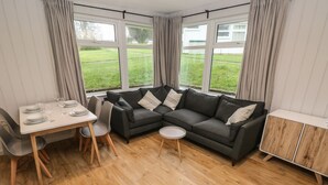 A modern living room with a sectional sofa, a dining table with chairs, and a small side table. - Saltwater (Haverfordwest)