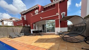 A red building with a swimming pool, outdoor seating, and a covered area. - Modern villa with private pool on 5 star Golf Resort (Torre-Pacheco)
